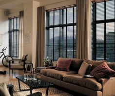 a living room filled with lots of furniture and windows covered in blind shades next to a bike