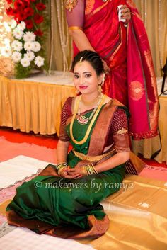 a woman sitting on the ground in a green sari with her hands up to her chest