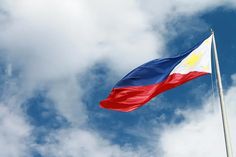 a flag flying high in the sky with clouds behind it on a sunny day,