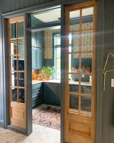 an open door leading to a kitchen with blue walls and wooden trim on the doors