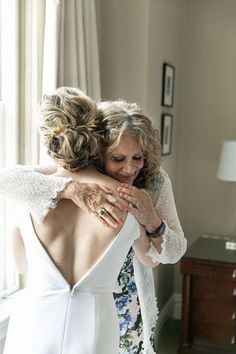 two women hugging each other in front of a window