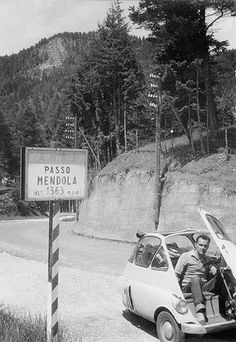 a man sitting in the back of a small car next to a sign that says passo mendela