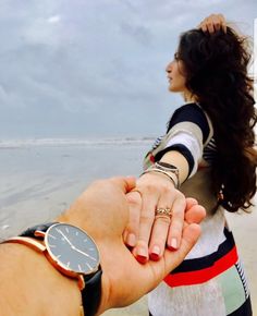 two people holding hands while standing on the beach