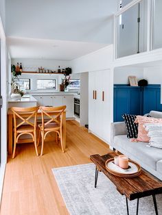 a living room filled with furniture next to a kitchen and dining room table on top of a hard wood floor