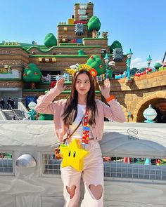 a woman standing in front of a castle with a star on her chest and hands up