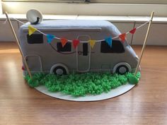 a cake shaped like a camper is on a table with green grass and bunting