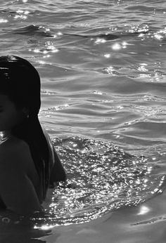 black and white photo of woman in water with sun reflecting off the water's surface