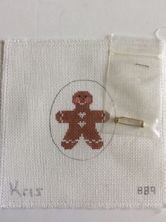 a cross - stitch teddy bear on a white cloth with a needle and thread in it