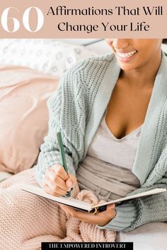 a woman sitting on a bed writing in a book with the title 60 affirmations that will change your life