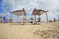 two beds sitting on top of a sandy beach