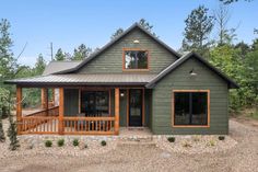 a small green house in the middle of a wooded area with lots of trees around it