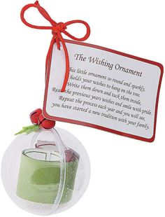 a glass ornament with a red ribbon hanging from it's side and a card attached to the front