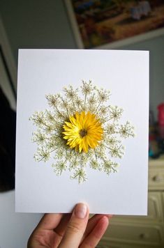 a person holding up a card with a yellow flower on it