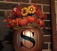 a pumpkin with flowers in it sitting on top of a shelf next to a brick wall