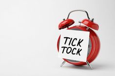 a red alarm clock with a sign that says tick tock on it's face