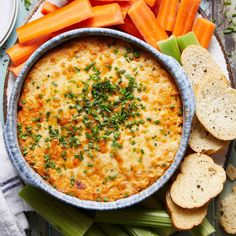 carrots, celery and crackers on a plate with dip in the middle