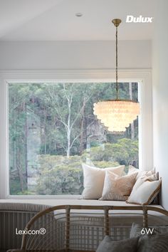 a window seat with pillows on it and a chandelier hanging from the ceiling