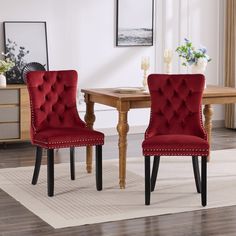 two red chairs sitting in front of a wooden table on top of a white rug