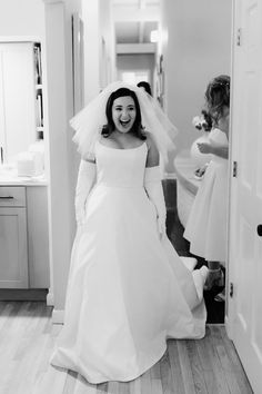 a woman in a wedding dress and veil is smiling at the camera as she walks into her room