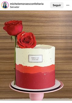 there is a red and white cake with two roses on the top one has a name tag