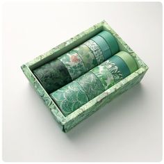 four rolls of washi paper in a green box on a white surface with the lid open