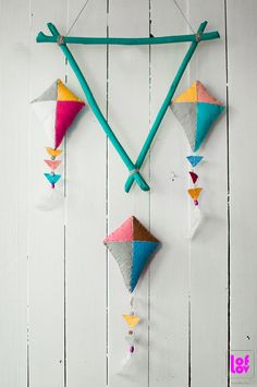 colorful kites hanging on the side of a white wooden wall with string attached to it