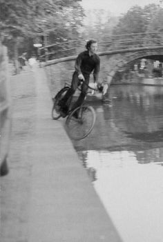 a man riding a bike down a river next to a bridge