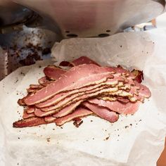 slices of ham sitting on top of parchment paper next to a frying pan filled with meat