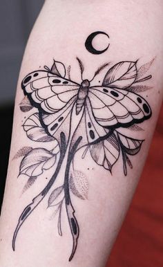 a black and white butterfly tattoo on the right arm with a crescent moon behind it