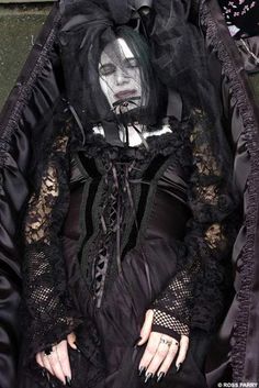 a woman dressed in black sitting on the ground