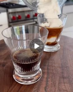 two glasses filled with ice cream on top of a wooden table next to a blender