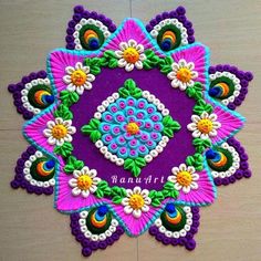 an intricately decorated purple and green design on a wooden surface with the words ranga art written below it