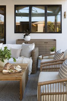 a living room with wicker furniture and large windows on the side of the house