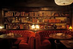 two red booths with tables and chairs in front of bookshelves filled with books