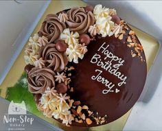 a birthday cake with chocolate frosting and flowers on it's side, sitting in a box