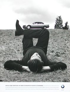 a man laying on the ground in front of a car