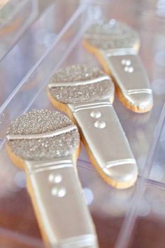 three decorated cookies sitting on top of a clear plastic container filled with frosted icing