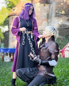 two women dressed in costumes standing next to each other on the grass with chains around their ankles