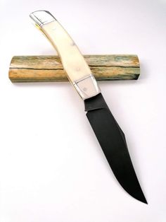 a knife is laying on top of a piece of wood with a blade sticking out of it