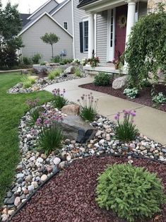 a front yard with rocks and flowers on the lawn