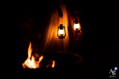 two lanterns lit up in the dark with fire coming out from behind them at night