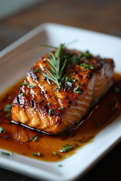 a piece of salmon on a white plate with sauce