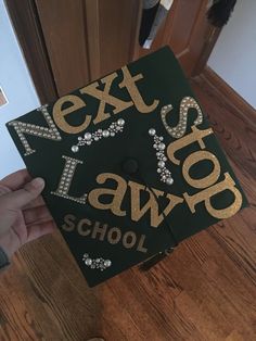 a person holding up a black and gold graduation cap with the words next to law school written on it