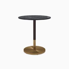 a round table with a black marble top and gold metal base, against a white background