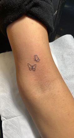 a woman's arm with three butterflies tattoo on the back of her left arm