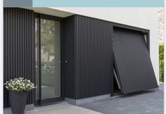 a planter with flowers in front of a black door on the side of a building