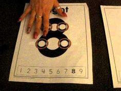 two children's hands on top of a paper with numbers and circles in it