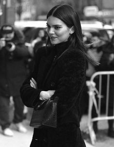 a woman is walking down the street with her hand on her hip