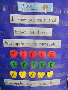 an apple themed bulletin board with words and pictures on the bottom, in front of a blue barrel