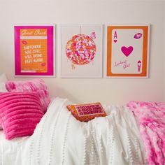 a bed with pink pillows and pictures on the wall